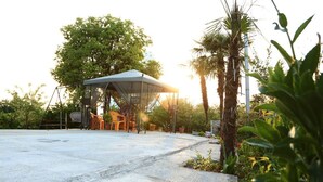 An outdoor area with a covered seating area, a basketball court, and surrounding greenery. - Tamara bed and breakfast :-) (Batumi)