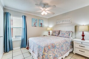 A bedroom with a bed, two wall-mounted lamps, a ceiling fan, and a window with curtains.