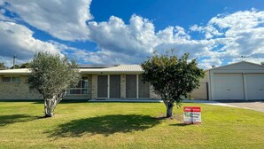 A two-story house with a garage, a lawn, and two trees. - Sandy Paws - Burrum Heads- Walk to Beach -3BR- Aircon-Pool table (Burrum Heads)