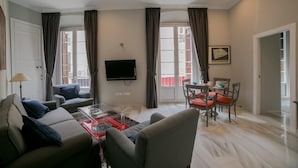 Una sala de estar con sofá, sillón, mesa de centro y una zona de comedor con sillas y mesa.