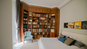 Un dormitorio con una amplia estantería, una cama con muchos cojines y una silla.