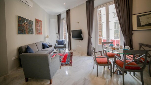 Una sala de estar moderna con un sofá, sillones, una mesa de centro y un comedor con sillas y una mesa.