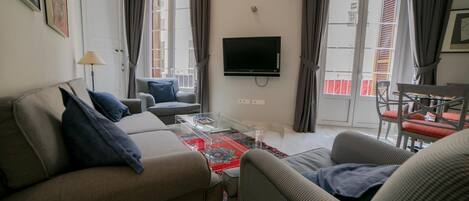 A living room with a sofa, armchairs, a coffee table, and a TV.