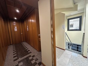 A hotel hallway with wooden paneling, a patterned carpet, and a staircase leading to a landing with a window. - Host Bari centrale - Hostel (Bari)