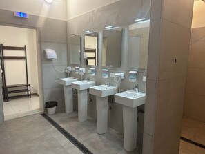 A modern bathroom with three sinks, mirrors, and hand dryers. - Host Bari centrale - Hostel (Bari)