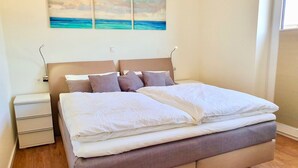 Ein ordentlich bezogenes Bett mit Kopfteil, Nachttisch und Schubladeneinheit.