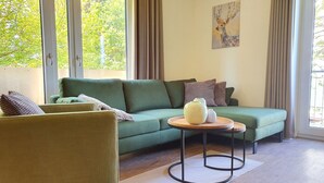 Ein Wohnzimmer mit einem grünen Sofa, einem runden Couchtisch und einem Gemälde an der Wand.