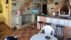 A kitchen with a tiled backsplash, a television, and bar stools.