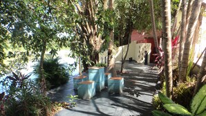 A pathway lined with trees and planters, leading to a building with a red wall.