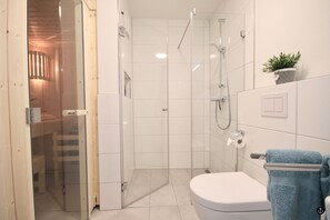 Um banheiro moderno com box de vidro, vaso sanitário branco e porta-toalhas com uma toalha azul.
