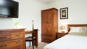 Une chambre à coucher comprenant un lit, un bureau, une chaise, une armoire et un téléviseur.