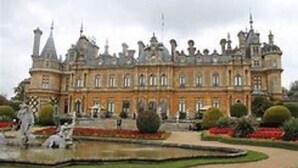 Un grand bâtiment historique à la façade symétrique, doté de nombreuses tours et d’une cour centrale agrémentée d’une fontaine et de statues.