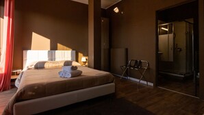 A modern hotel room with a large bed, a sitting area, and a glass-enclosed shower. - Dolci Emozioni (Bari)