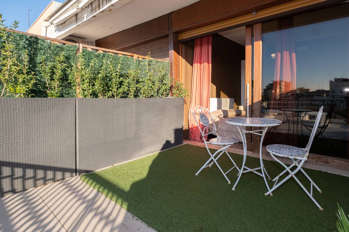 Une terrasse avec du gazon synthétique, une table et des chaises.