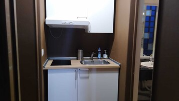 A compact kitchenette with a sink, a small cabinet, and a bottle of hand soap.