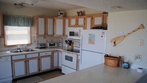 Eine kleine Küche mit Holzausstattung, einer Mikrowelle, einem Toaster und einem Kühlschrank.