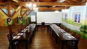 A long conference room with wooden tables and chairs, chandeliers, and a white screen at the front. - Usługi Noclegowe 17 (Ostrow Mazowiecka)
