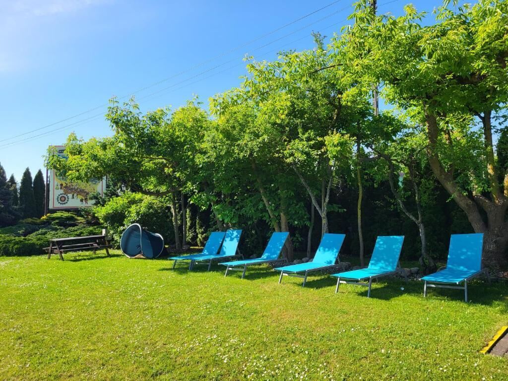 A row of blue lounge chairs under trees in a grassy area.