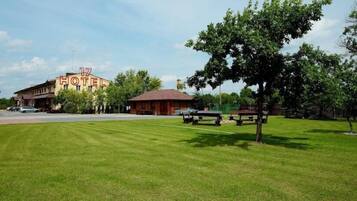 Un hotel con un letrero grande, un estacionamiento y un área verde con mesas de picnic.