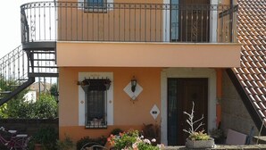 A two-story building with a balcony, potted plants, and a tiled roof. - B&B Villa Milena (Ariano Irpino)