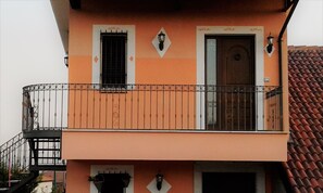 Un edificio de dos plantas con balcón, puerta y ventana.