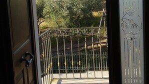A door leading to a balcony with a metal railing, a view of trees and a distant landscape. - B&B Villa Milena (Ariano Irpino)