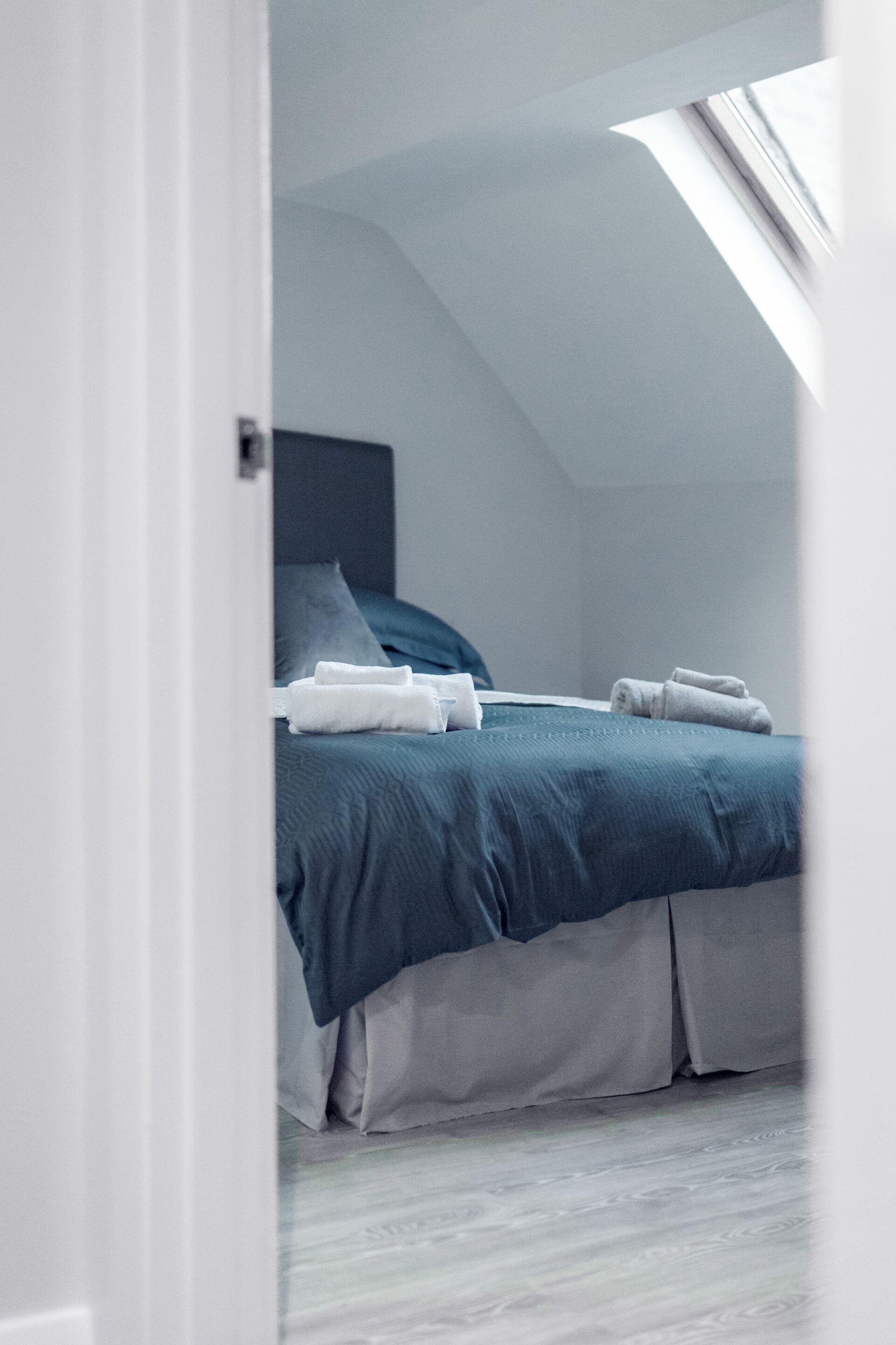 A bedroom with a bed, pillows, and neatly folded towels.
