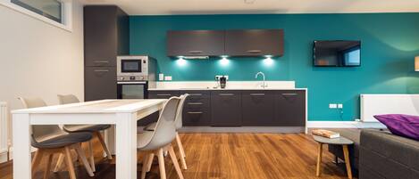 A modern kitchen with dark cabinets, a white countertop, and a built-in microwave.