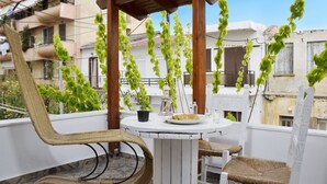 A balcony with wicker chairs, a small table, and hanging plants. - Urban Studios Manos (Chania)