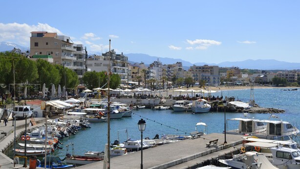 A marina with boats docked, a clear sky, and buildings in the background. - Urban Studios Manos (Chania)
