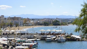 A marina with boats docked, a beach, and buildings in the background. - Urban Studios Manos (Chania)