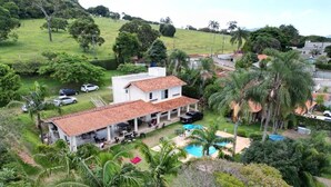 Ein Haus mit einem Ziegeldach, einem Swimmingpool und einem Garten mit Palmen.