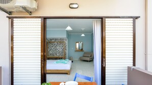 A room with a bed, a chair, a table with plates and glasses, and a small plant. - Katerina Apartments 1 (Chania)
