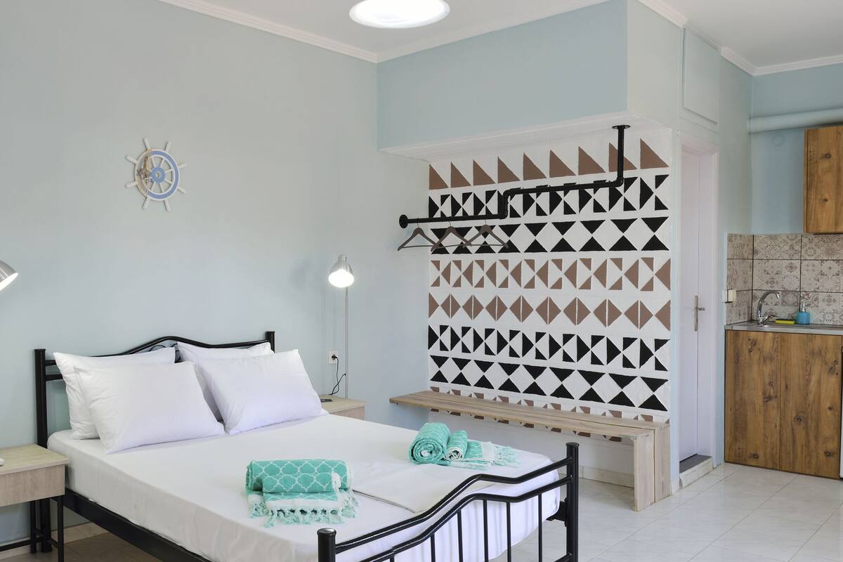 A compact room with a bed, a kitchenette, and a small dining area.