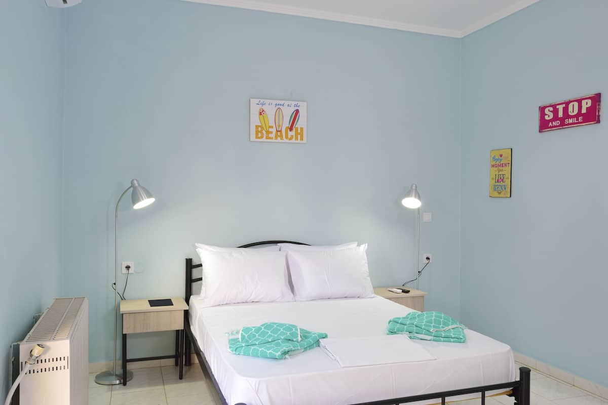 A bedroom with a bed, two bedside tables, a desk, a heater, and wall decorations.