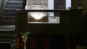 A staircase with a stone wall and a door with a metal gate. - Katerina Apartments 1 (Chania)
