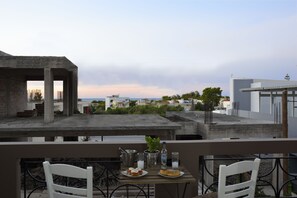 Ein Balkon mit Tisch für zwei Personen, Blick auf eine Stadtlandschaft mit Gebäuden und Meer.