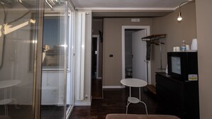 A modern living room with a glass door leading to a balcony, a small round table, a sofa, and a television on a black cabinet. - CconfortHotels R&B Cavour (Bari)