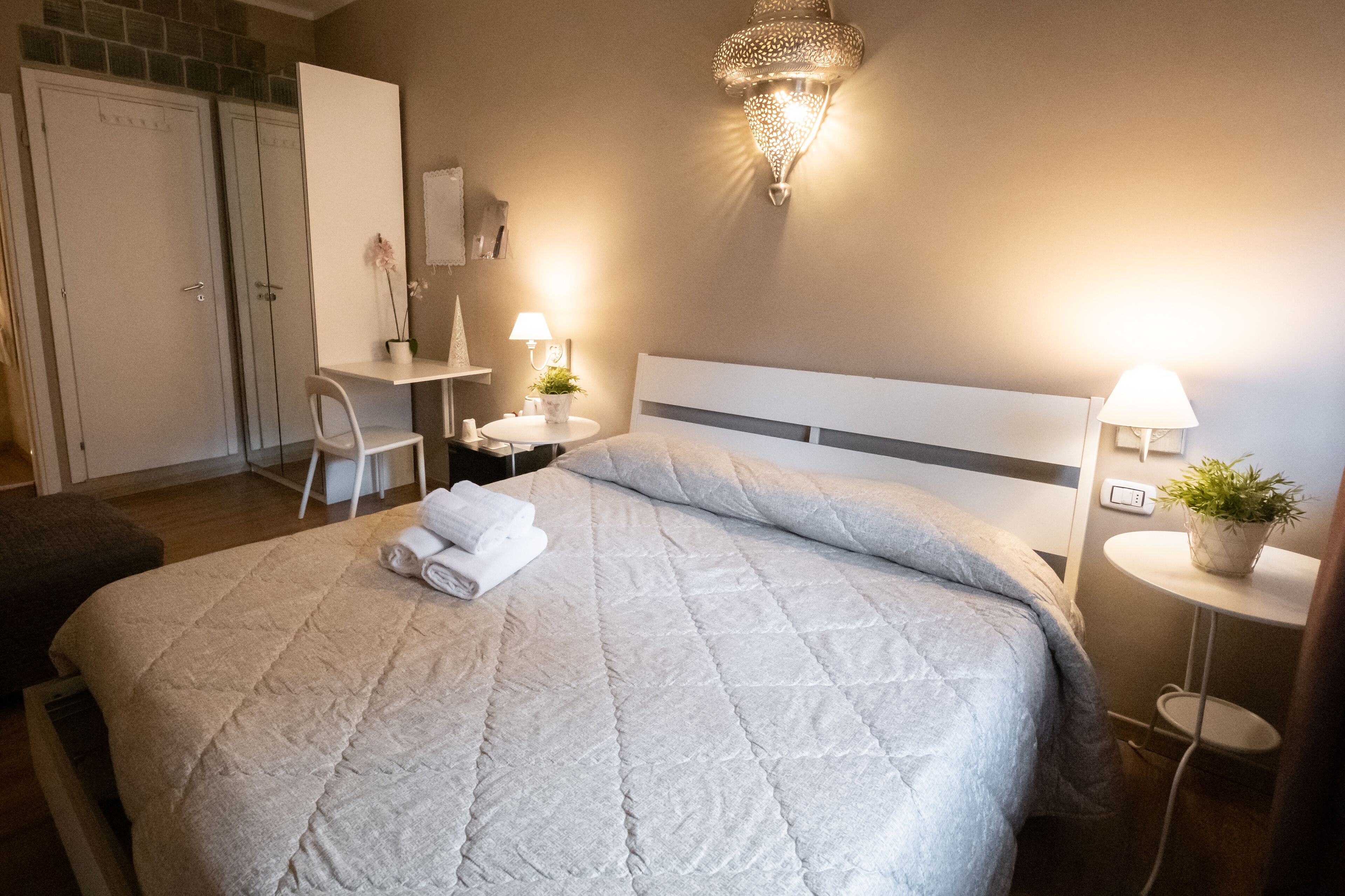 A neatly arranged bedroom with a large bed, a desk, and a chair.