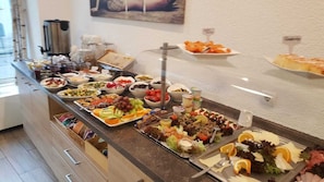 Un buffet proposant une variété de plats, notamment des fruits, des salades et des viandes.