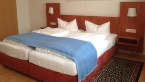 A hotel room with a bed, a painting of a beach scene, and a nightstand with a lamp. - Altstadt-Garni (Bad Windsheim)