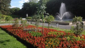A park with a fountain, flower beds, and trees. - Altstadt-Garni (Bad Windsheim)