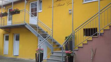 A yellow building with a staircase and flower planters.