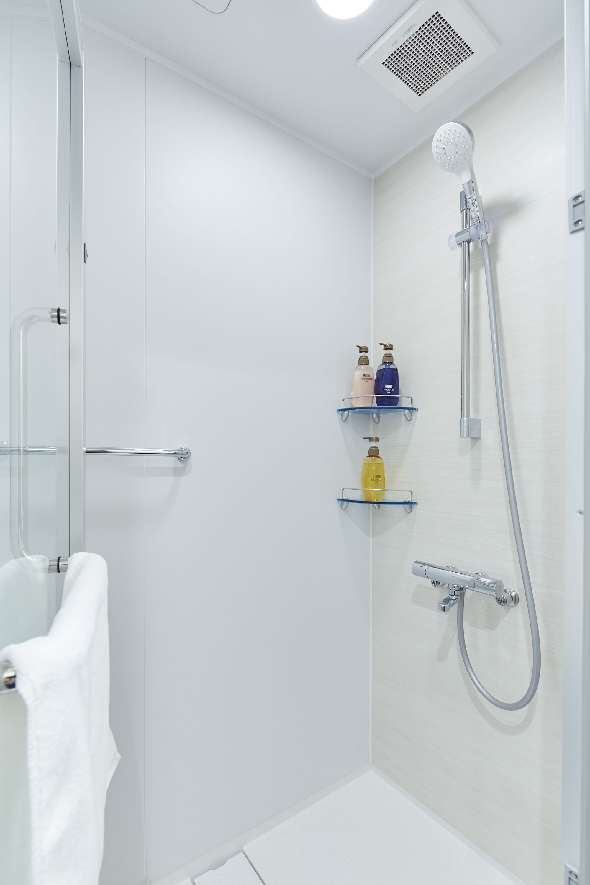 Un baño moderno con cabina de ducha de vidrio, cabezal de ducha manual y un perchero para toallas.