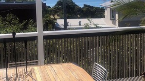A wooden table and chairs on a balcony with a view of the sea and a bridge. - DRIFTWOOD SEVENTEEN BOOROO (Pambula Beach)