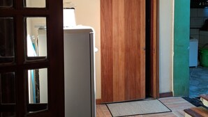 Um quarto com porta de madeira, frigorífico branco e chão em padrão herringbone.