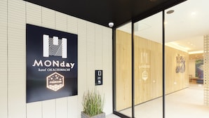 A hotel entrance with a large sign reading "MONday hotel OKACHIMACHI PREMIUM" and a reception area visible through glass doors. - hotel MONday Premium Ueno Okachimachi (Tokyo)