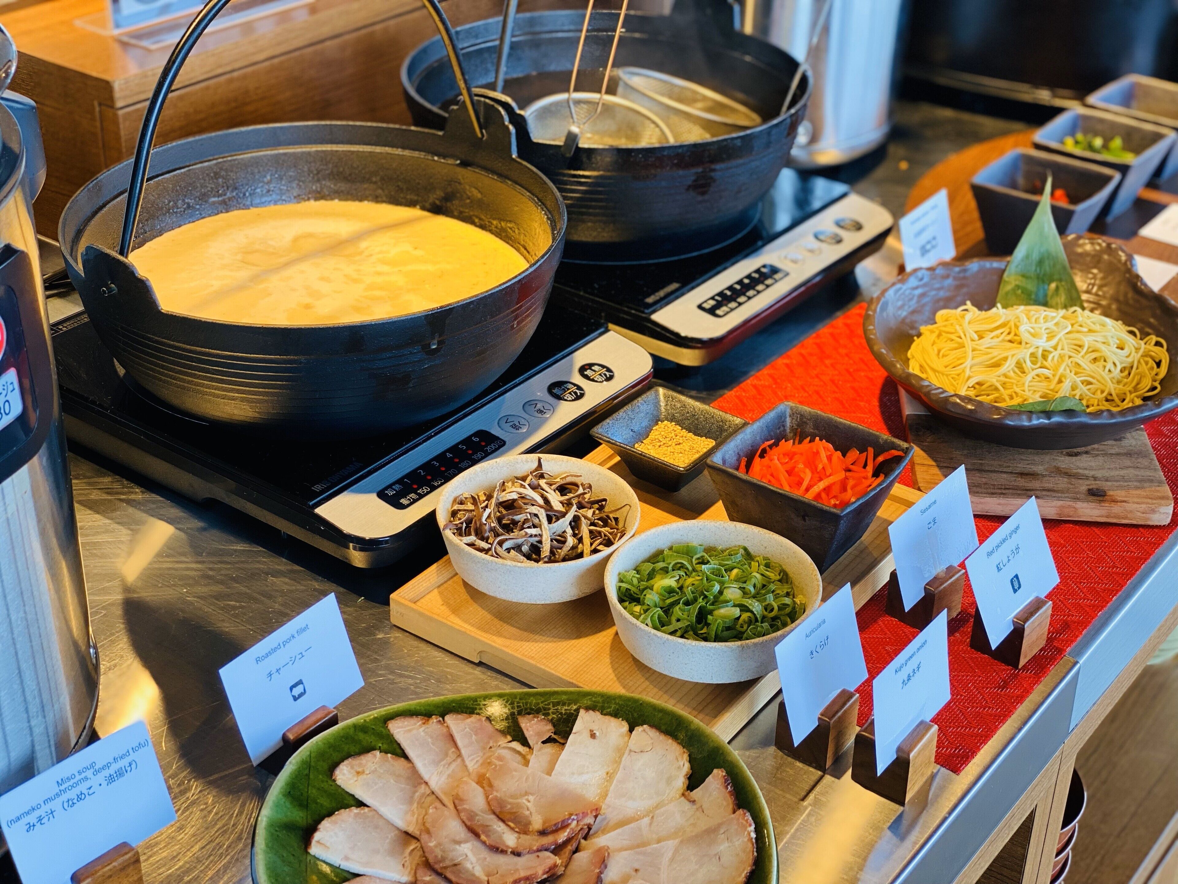 Ein Buffet mit verschiedenen Speisen, darunter eine Suppenterrine, Schalen mit Gemüse und geschnittenem Fleisch.