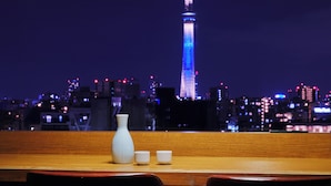 A table with a white vase and two cups, overlooking a cityscape with a lit tower at night. - hotel MONday Premium Ueno Okachimachi (Tokyo)
