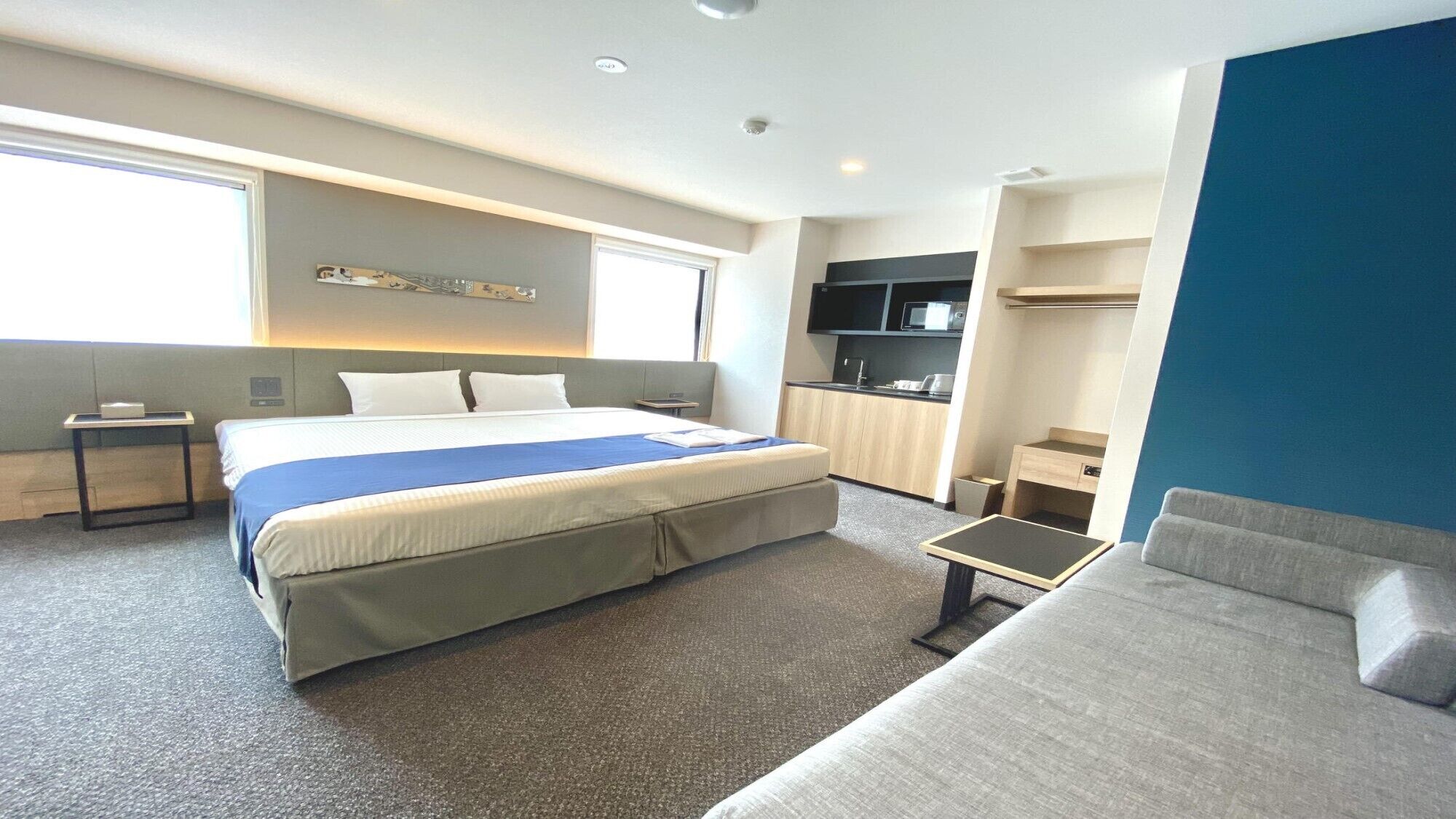 Une chambre d’hôtel équipée d’un lit, d’un canapé, d’un bureau, d’une télévision et d’une kitchenette.